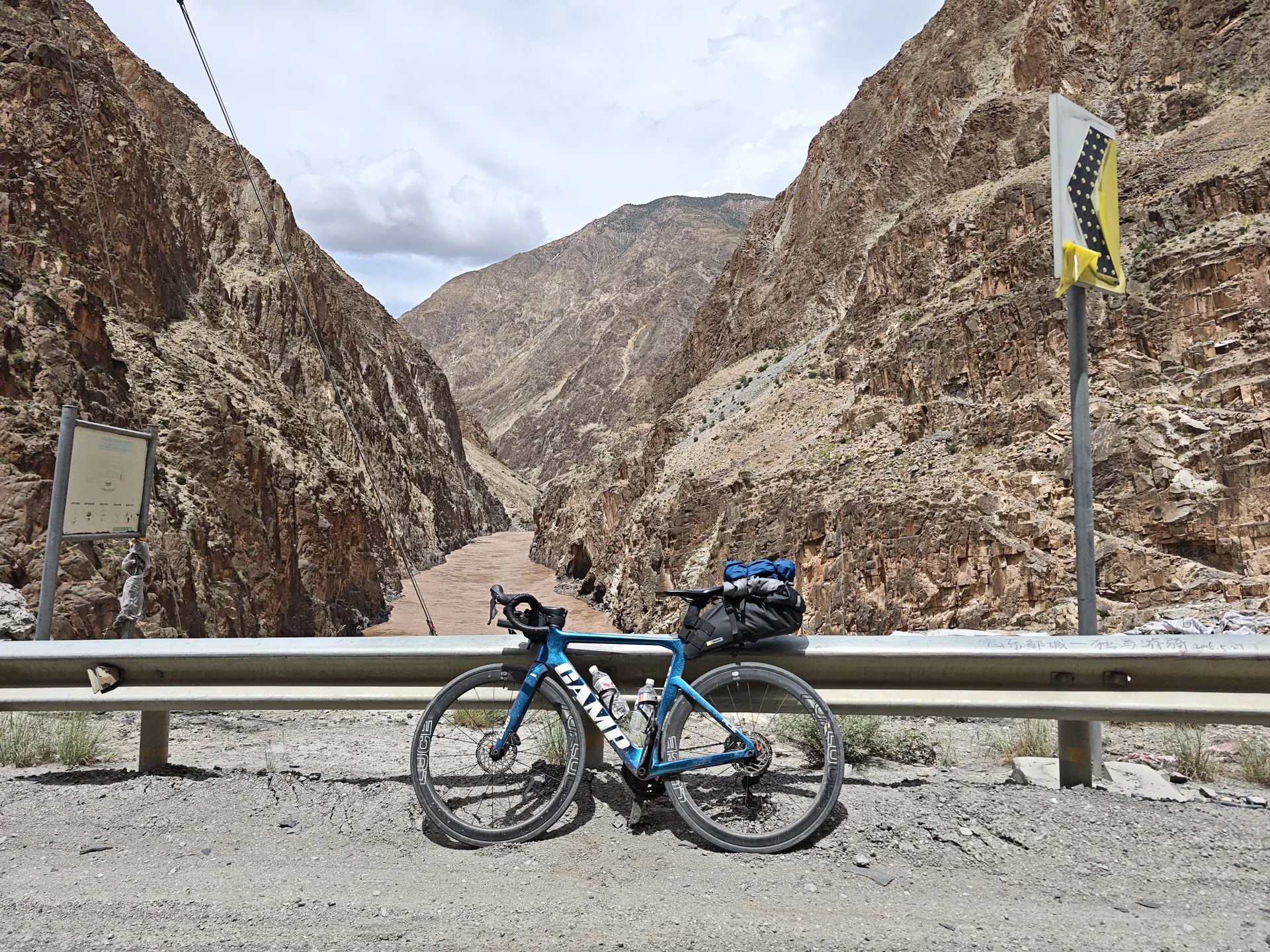 A touring bicycle beside a guardrail in a rocky valley