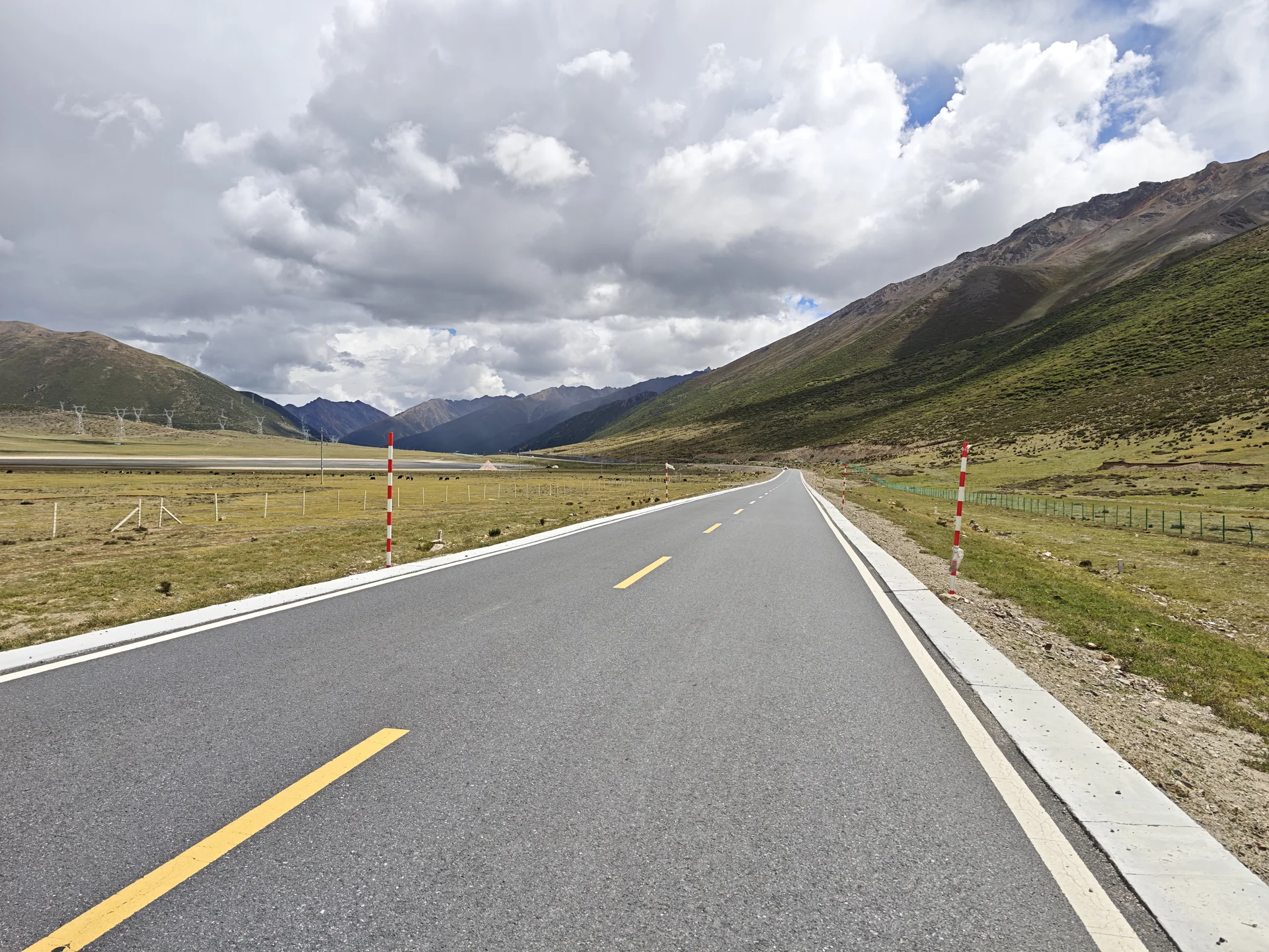 An empty road crossing a broad highland valley