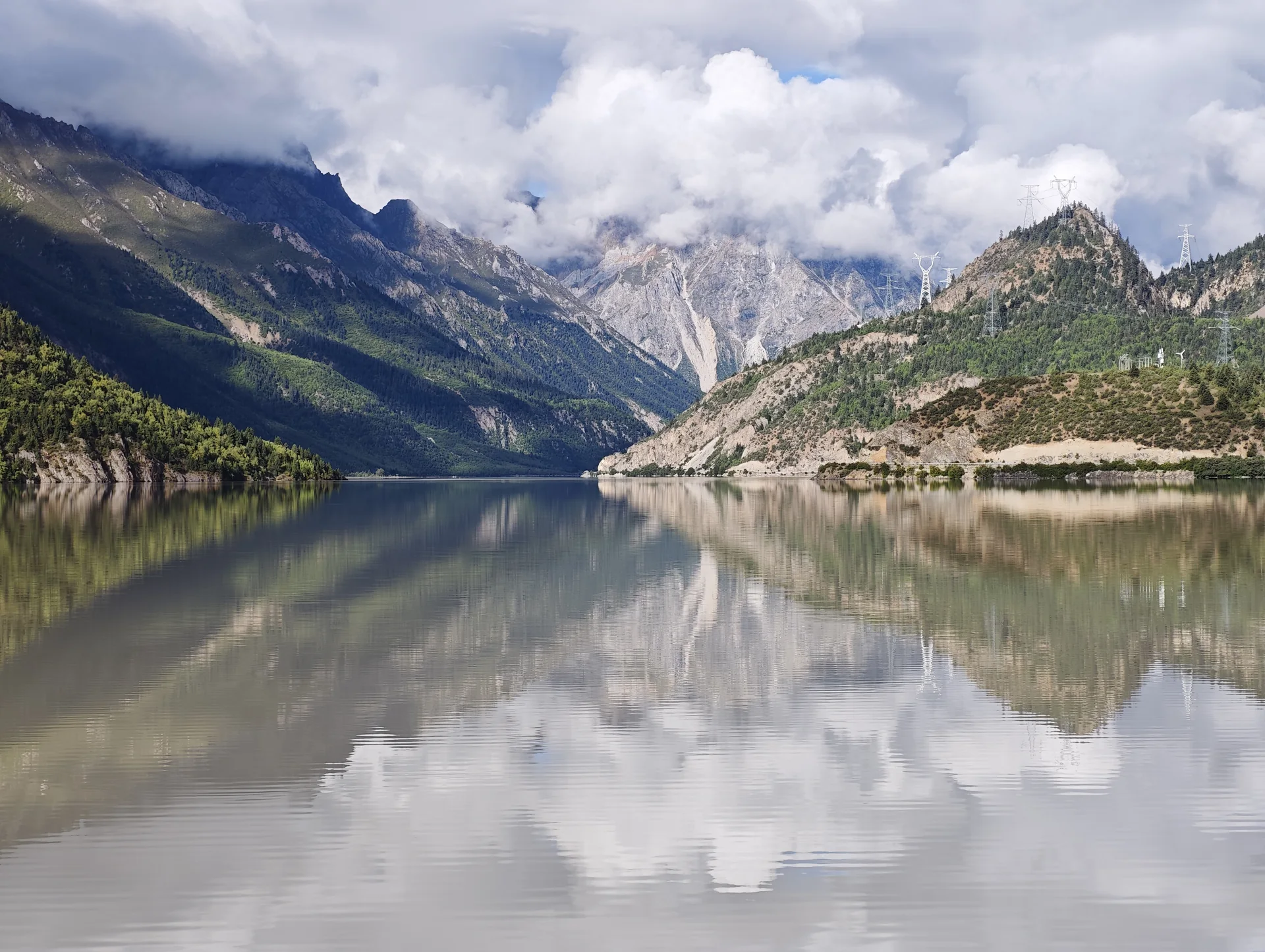 A mountain lake reflecting clouds and distant peaks