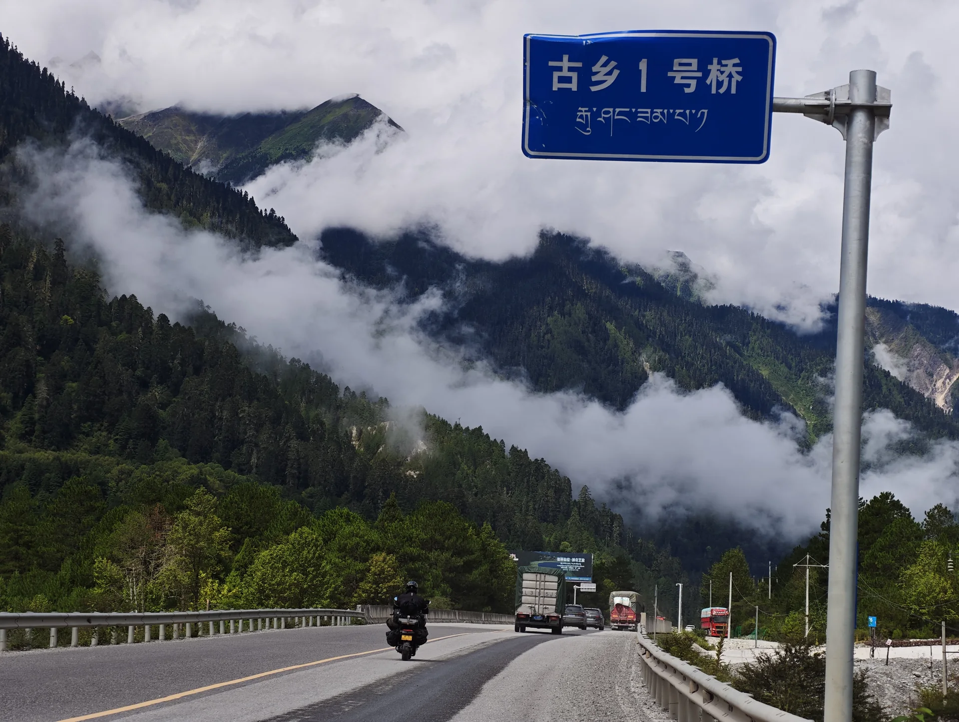A highway sign above a foggy mountain road