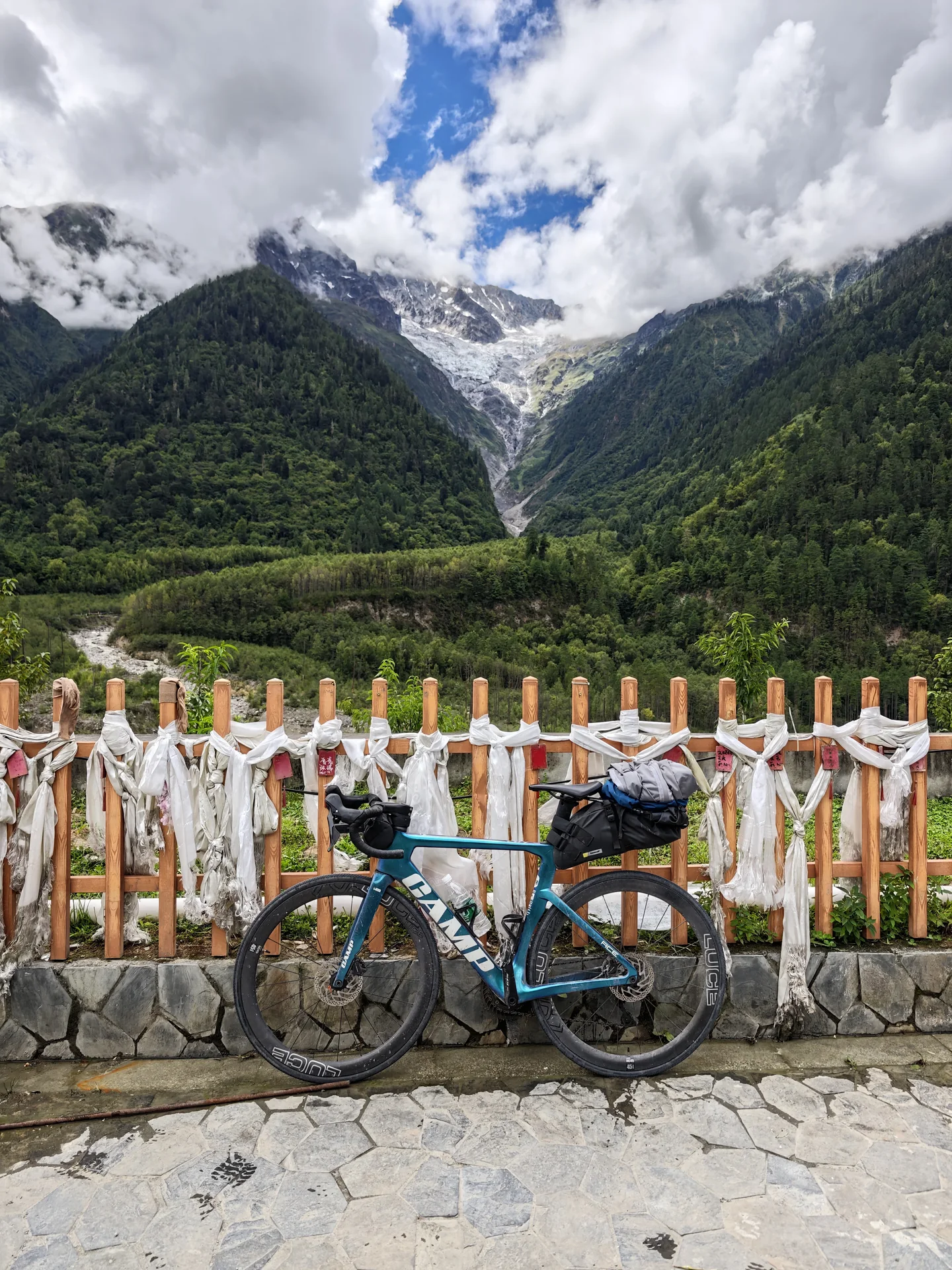 A cyclist with a bicycle beside a mountain pass fence