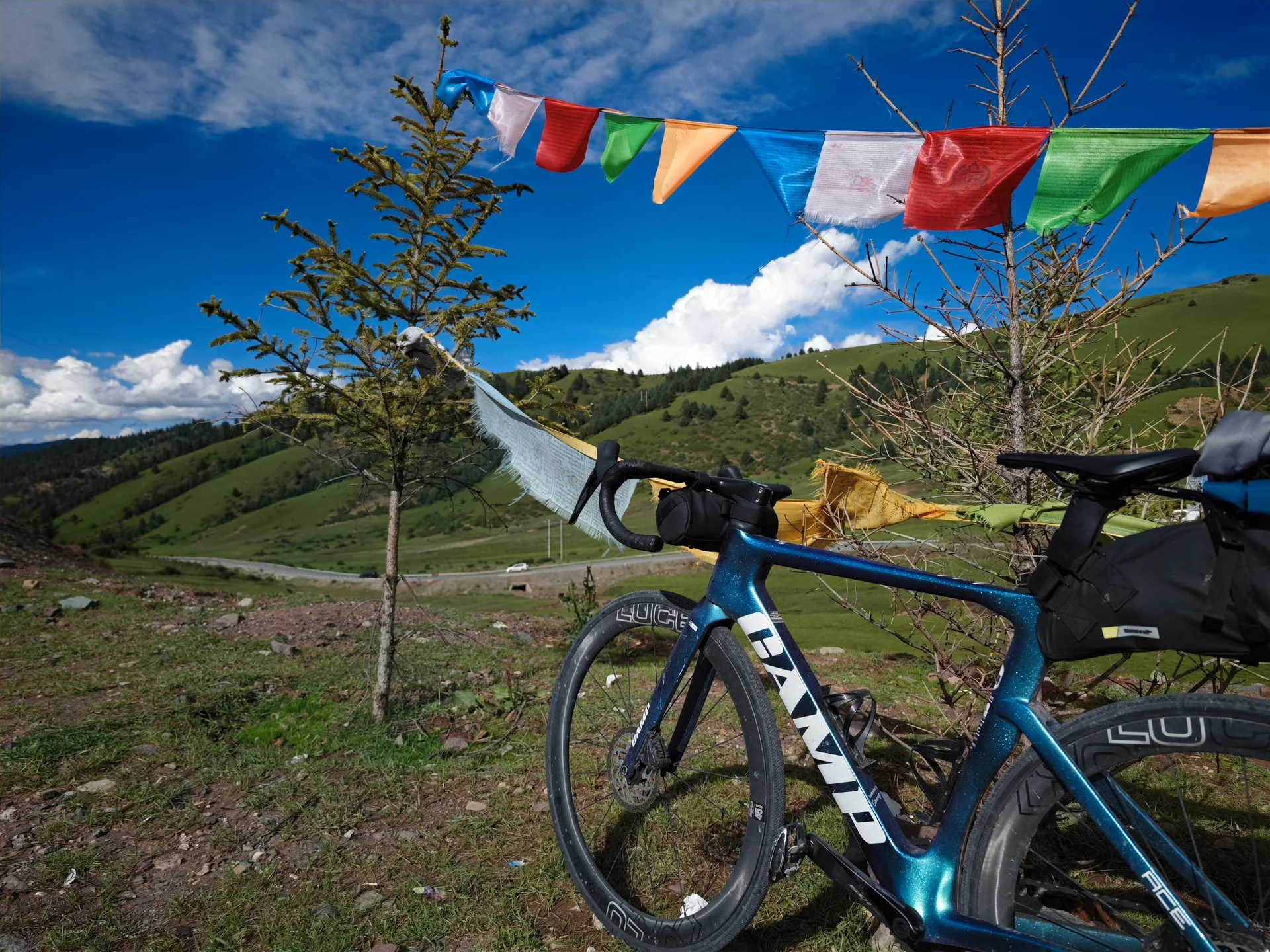 A touring bicycle beneath prayer flags on a hillside