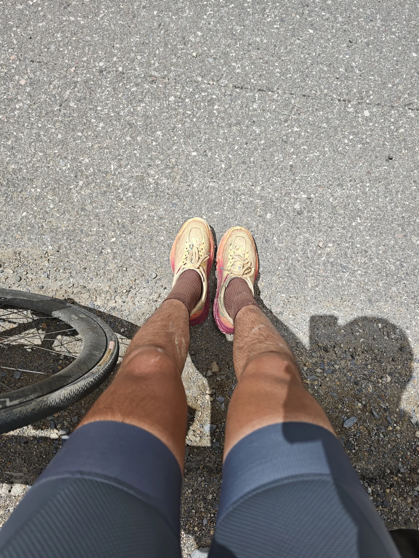 A cyclist looking down at their shoes on a mountain road