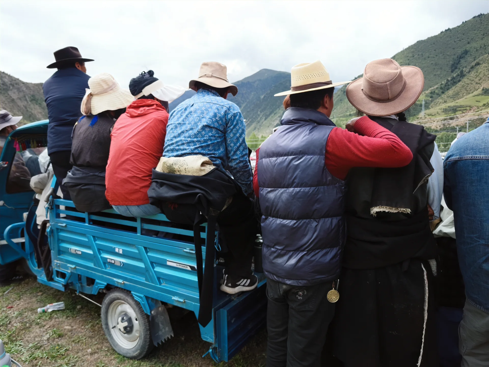 People riding in the back of a blue truck at a mountain event