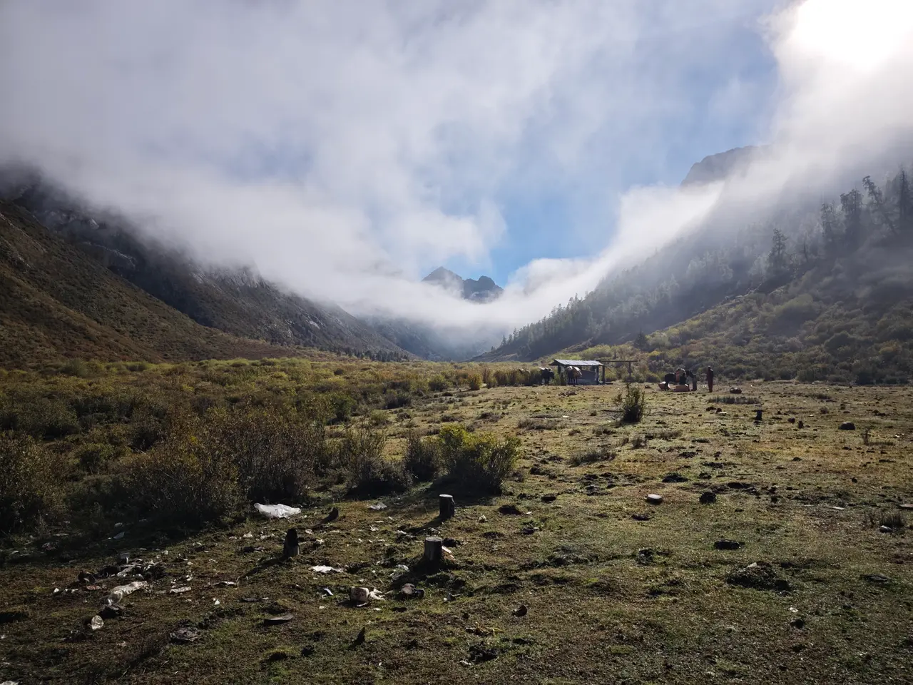 厚云从四周山体压向谷底，湿地和石滩被困在一只灰色碗底。