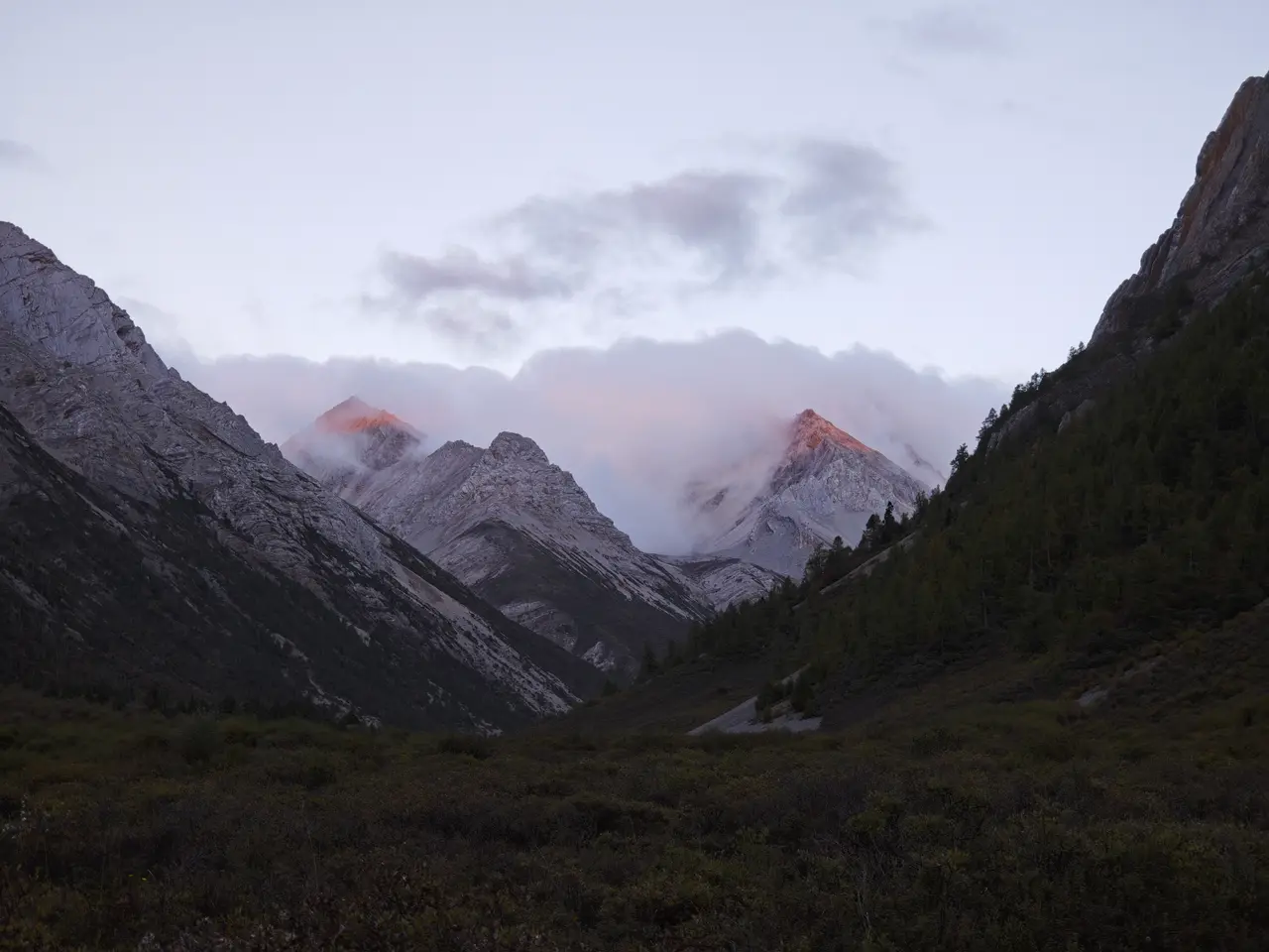 粉紫色余晖落在山口尖峰上，昏暗谷底和暖色山尖形成强烈对比。