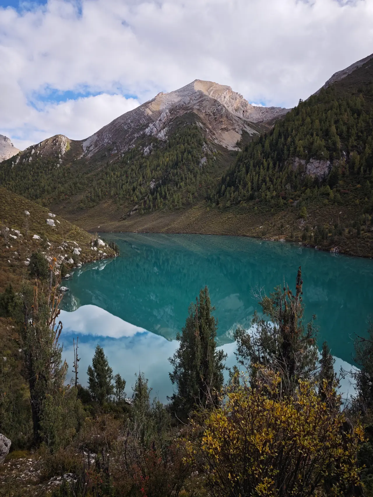 从山坡高处俯看一汪蓝绿色湖水，岸边树木和岩坡把湖面围成一只眼睛。