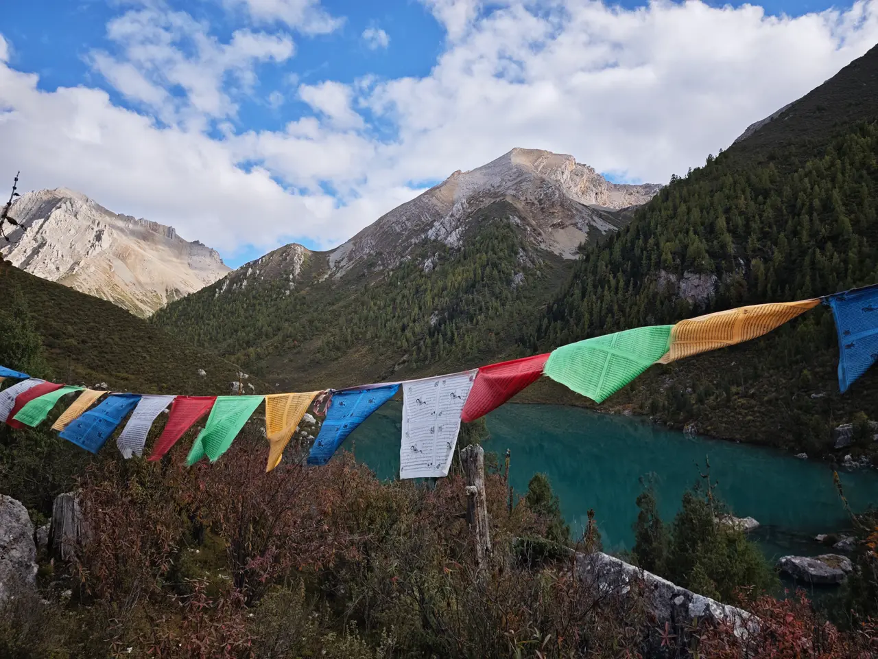 五色经幡横跨在湖水前方，蓝绿色海子安静躺在群山之间。